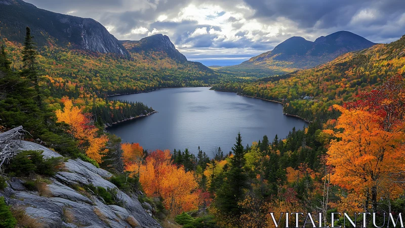 Mountain lake valley with dense autumn forest and clouds.