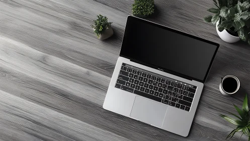 Laptop on gray wooden desk with plants and black coffee mug