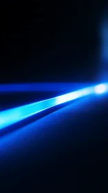 Electric blue light beam cutting through dark space.