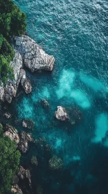 Rocky tropical shoreline meets vivid turquoise sea from above.