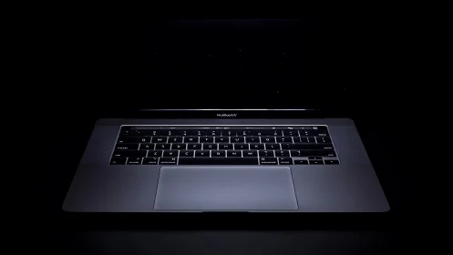 Backlit aluminum laptop in low-key studio isolation lighting.