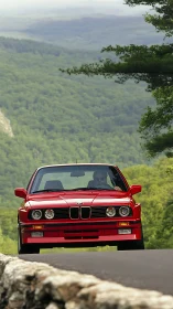 Classic red BMW cruising through peaceful mountain curves.