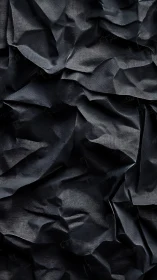Crumpled dark fabric texture with deep folded shadows.