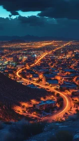 Urban nightscape with winding arterial road and distant hills.