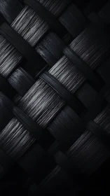 Interwoven charcoal strips under dramatic side lighting.