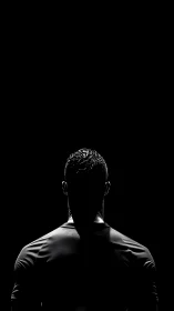 Silhouetted male athlete stands under narrow overhead light
