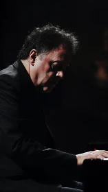 Solitary concert pianist in dramatic low-key stage lighting.