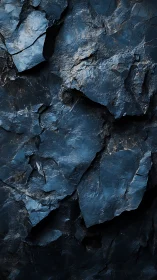 Dark fractured rock surface shows layered angular textures