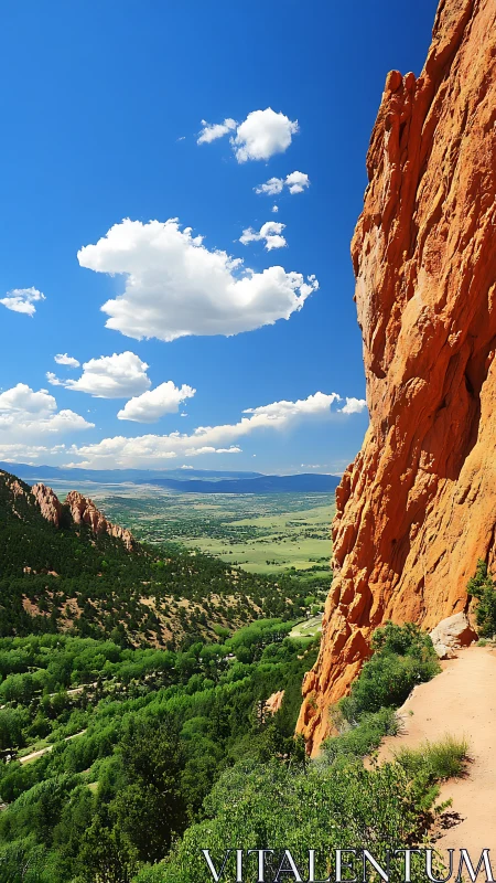 Sunny red rock trail overlooking a bright green valley.