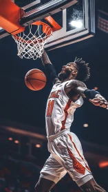 Basketball player executing dunk under indoor arena hoop.