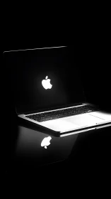 Sleek illuminated laptop glows against deep black backdrop.