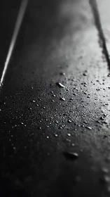 Glistening raindrops rest softly on a quiet dark surface