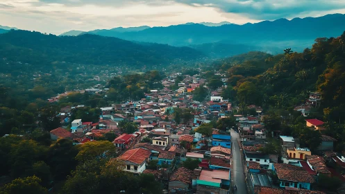 Mountain town skyline under misty blue ridgeline at dusk.