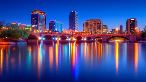 Neon river reflections beneath a sapphire city bridge night.