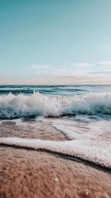 Foamy shoreline wave under soft pastel coastal sky.