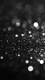 Monochrome bokeh lights across dark blurred background.