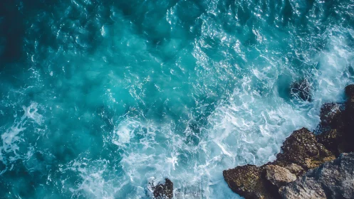 Turquoise ocean waves break against rugged coastal rocks.