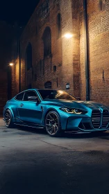 Blue performance coupe parked by illuminated brick wall.