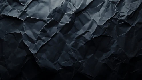 Dark crumpled paper texture under soft directional light.