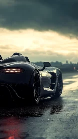 Rear view of black sports car on wet track at dusk.