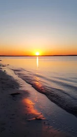 Sun aligns with horizon over calm sea and reflective shoreline