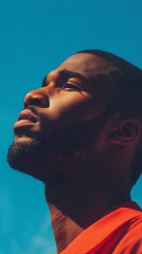 Man&rsquo;s side profile faces bright sunlight against clear sky