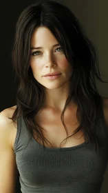 Portrait of woman in gray tank top on dark backdrop.