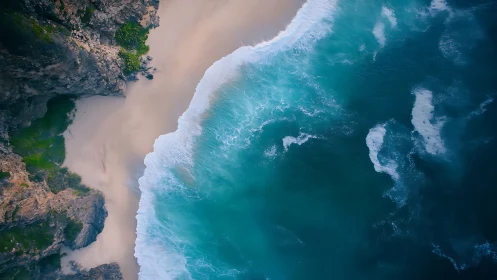Overhead coastal view shows surf meeting sand and cliffs