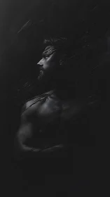 Moody low key portrait of muscular bearded man in profile.