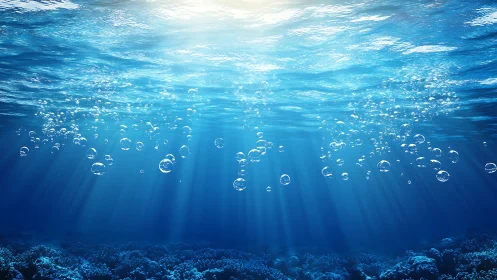 Sunlit underwater bubbles drift through clear blue ocean.