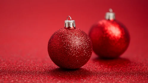 Glittered red Christmas baubles on monochrome bokeh backdrop