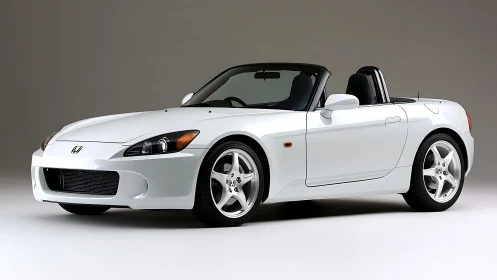 White two-seat convertible sports car in studio setting.