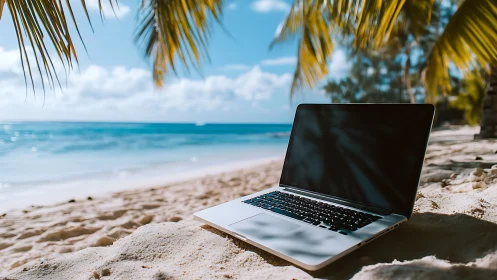 Laptop sits on tropical beach sand under palm fronds