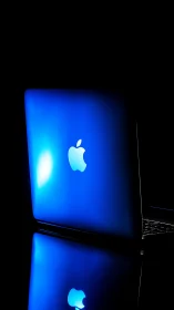 Backlit blue MacBook lid with specular highlight and mirror reflection
