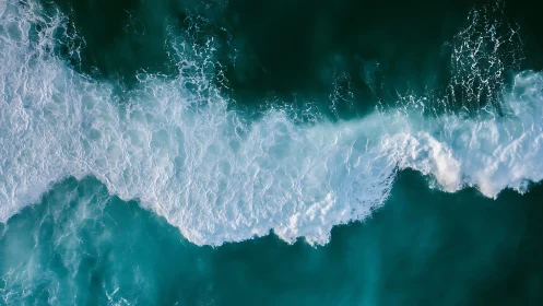 Aerial view of turquoise ocean waves and white surf line
