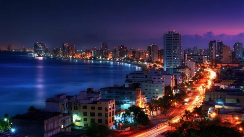 Coastal city skyline with illuminated waterfront at night.