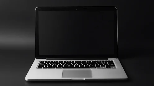Closed-screen silver laptop on dark seamless background.