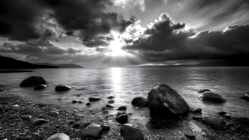 Monochrome sunset rays break through dramatic coastal clouds.