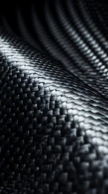 Curved carbon fiber weave under dramatic side lighting.