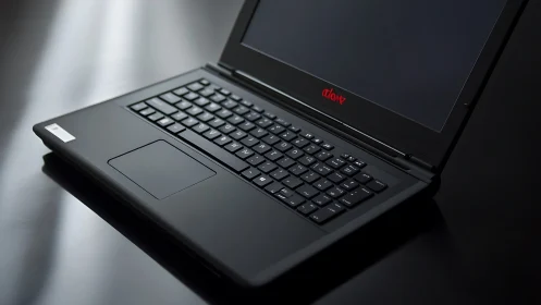 Black laptop computer on reflective dark surface in profile.