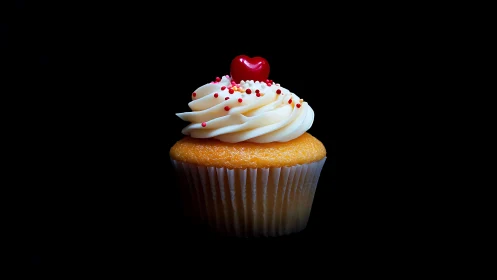 Decorative cupcake with white frosting and heart topper.