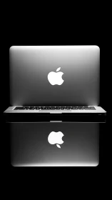 Closed silver laptop with glowing logo and clear reflection