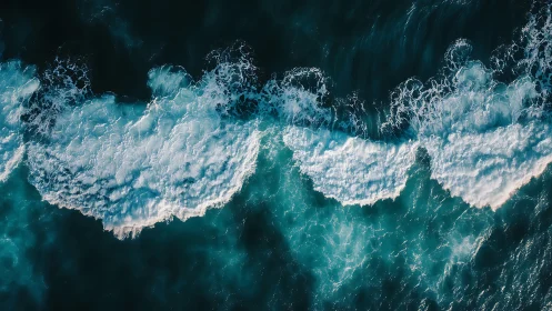 Cresting teal waves sketch bright foam ribbons from above