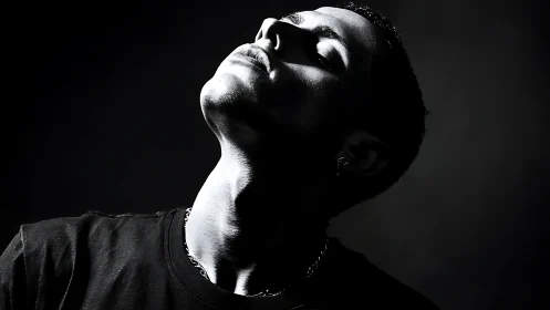 Shadow-lit portrait tilts into fierce monochrome reverie.