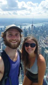 Smiling couple taking city skyline selfie from high viewpoint.