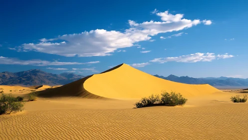 Golden desert dune under vivid blue sky with mountains.