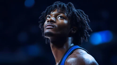 Under arena lights, focused basketball player in close-up portrait.
