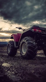Four-wheeled ATV stands on wet gravel under overcast sky