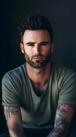 Moody tattooed man in soft studio portrait lighting.