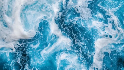 Turbulent blue seawater surface with dense white sea foam.